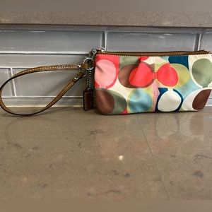Coach wristlet. Multicolored with cream background. Tan leather zip closure.
